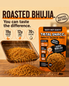 A retail package of Total Snacc Roasted Bhujia snack is shown alongside a metal scoop and pile of the roasted brown spice mix on a wooden surface. 